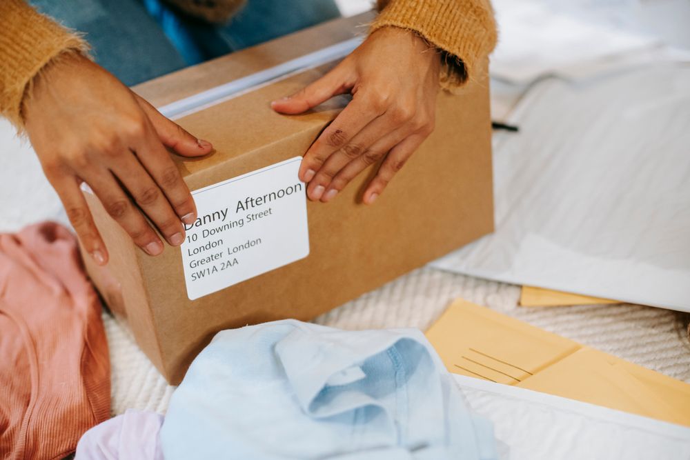 Hands preparing a cardboard parcel with a shipping label